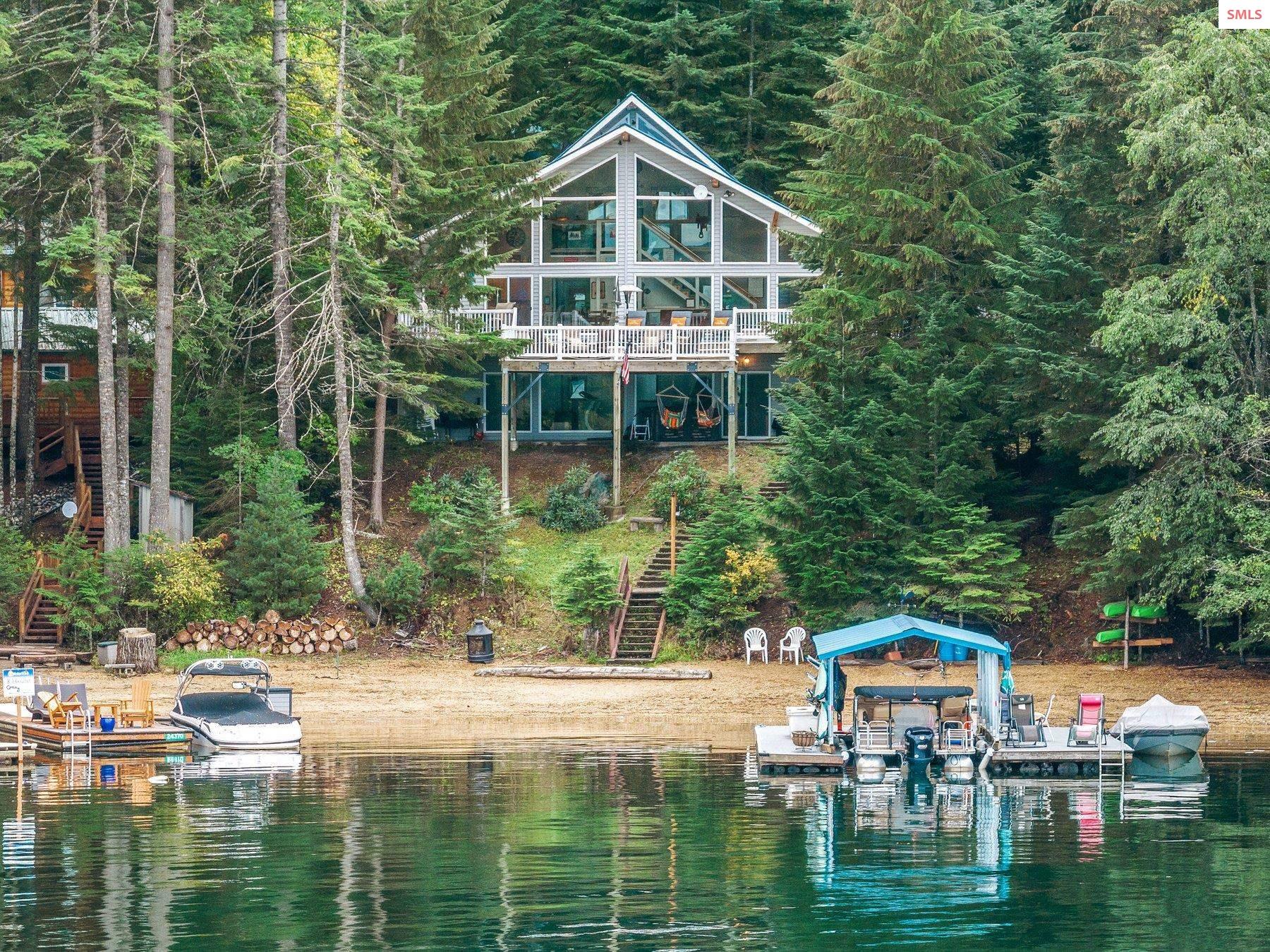 Create your own memories in Speakeasy Cove on Hayden Lake! This well-loved home is nestled on a large .59 acre wooded lot with 100' of RARE sandy-beach waterfront and complete with a boat dock! The main level features a master suite, bedroom, bathroom, and an open-concept kitchen & living room with floor to ceiling windows to enjoy the spectacular views with direct access to the expansive deck overlooking the lake. The lower level features a bedroom, bathroom, laundry, storage room, and a large family room with direct access to the lower covered patio. Upstairs you'll find the spacious loft that offers stunning lake views from a higher viewpoint. Numerous details and upgrades including gorgeous tongue & groove ceilings in the main living area, new flooring in the kitchen and basement, chef-inspired professional range, new 24kw Cummins backup generator & electric panel, new raised-seam lifetime metal roof and more. The 35'x26' deck has been re-cabled, re-surfaced with composite decking