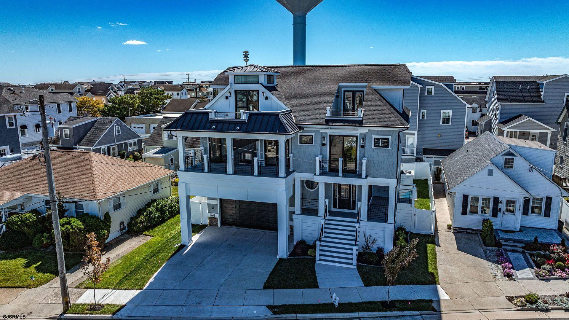 Immerse yourself in luxury with this breathtaking three story custom-built home in the exclusive Longport enclave. From the moment you enter this one-of-a-kind home, you are immediately surrounded by the finest finishes and craftsmanship. As you enter the first floor you are welcomed by a beautiful entryway and foyer which lead to a dramatic custom staircase and well appointed den area with a custom fireplace and bar area. This floor has it's own private bedroom and full bathroom tucked away for guests or multi-generational family members. As you continue onto the next floor you are met with an open floor plan living space, dining area, and gourmet chef's kitchen, custom fireplace, a full built-in bar area, beautiful powder room and outdoor access leading to the wonderful covered deck space and outside fireplace, perfect for entertaining. This floor is accented by plenty of windows allowing warm natural light to fill the space. On the alternate side of the home on this floor are three bedrooms all complete with on suite bathrooms. The top floor offers the primary suite with full bath and a steam shower.  Top floor also features a breathtaking water view from the private deck as well as a lounge area just off of the Master Bedroom. Take note of the elevator which accesses all levels in the building, Updated floors throughout and beautiful craftsmanship at every turn. This property was curated in partnership with Surroundings Interiors to create a fresh coastal aesthetic throughout the entire home.  The outside of this home is just as remarkable as the interior with several large decks, a private back yard complete with pool area.