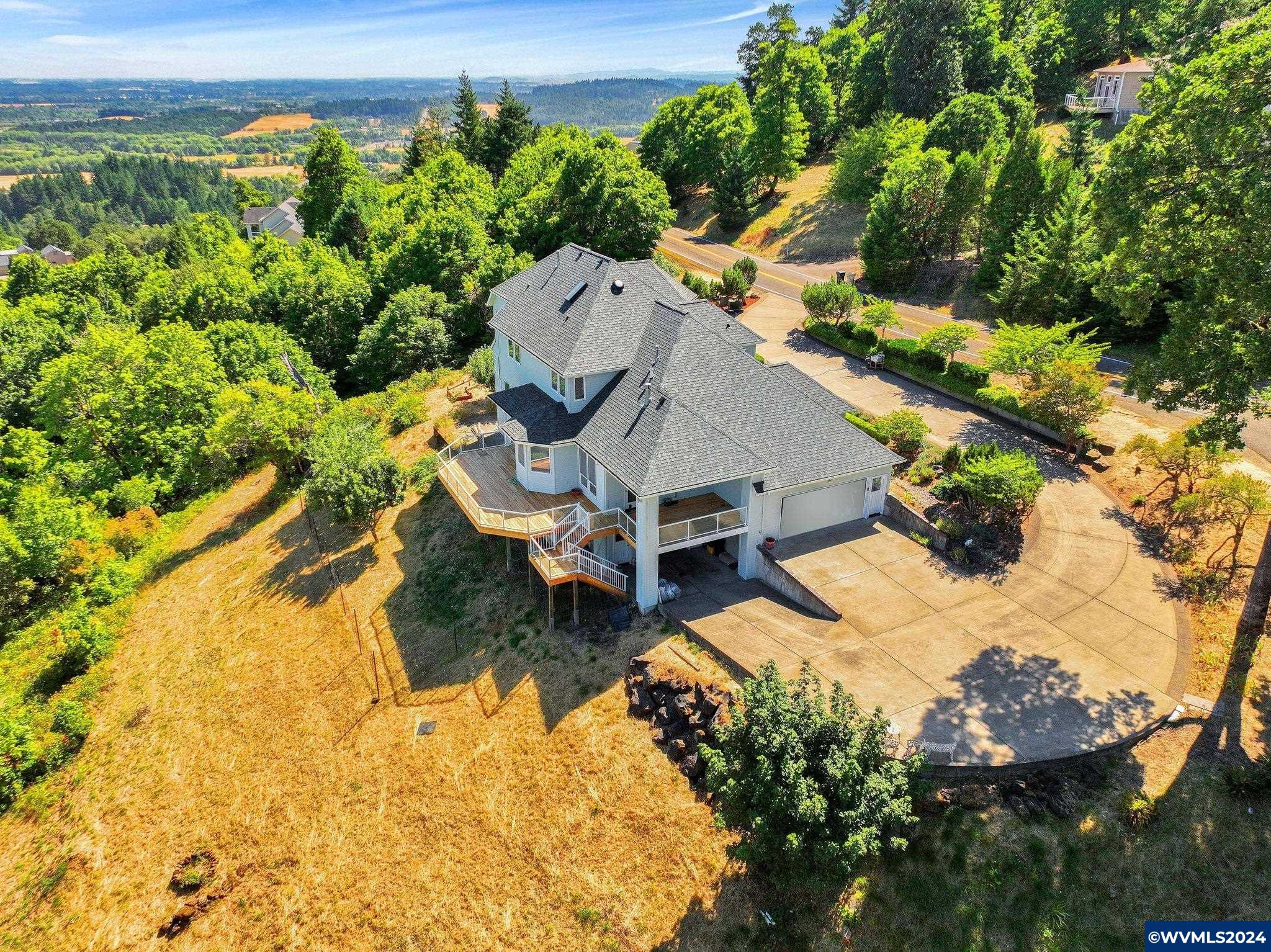 Perched atop the hill, this custom home by Russ Peterson offers breathtaking vistas from Mt. Hood to Three Sisters! Situated on 4.8 acres zoned RR-3, with the potential for a second lot, it's conveniently close to town. Inside, you'll find a formal living and dining area with a cozy gas fireplace, a spacious kitchen featuring granite countertops, a breakfast nook, stainless steel appliances, and a walk-in pantry. Work comfortably in the office, equipped with custom built-in shelves. The family room boasts another fireplace and opens onto a newly finished deck, perfect for soaking in the panoramic views. Retreat to the primary suite with its coffered ceilings and a luxurious tiled shower offering stunning vistas. Three additional bedrooms and an updated bathroom with a skylight complete the upper level. Downstairs, discover a wine cellar and a one-bedroom suite with a sliding door leading to a patio. The front landscaping is impeccably maintained and plumbed for an underground sprinkler system. Enjoy year-round comfort with 2-zone gas forced air heating and air conditioning. The oversized three-car garage includes a workshop and a potting area. Recent updates include a newer roof, kitchen renovations, fresh paint, deck enhancements, and more.