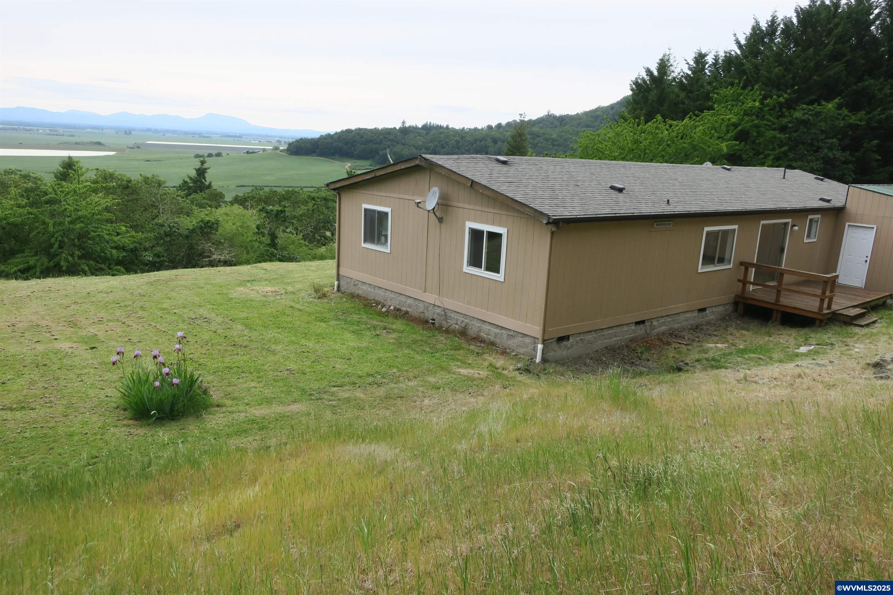 Experience the stunning views on this 2.7 treed acreage .  See the beautiful sunsets over Mary's Peak while sitting on your covered deck.  House has a den that could be used a a fourth bedroom.  Very close to town but Rual Feel